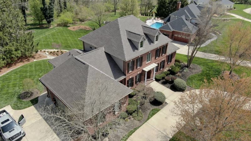 Aerial view of brick home with gray shingle roof