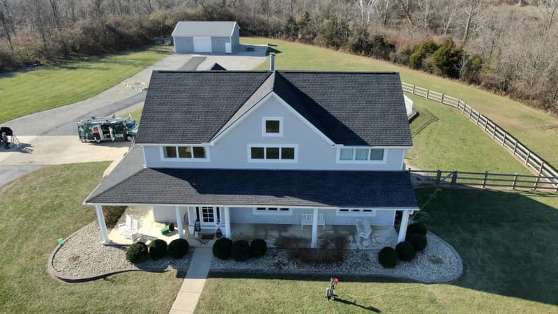 Farmhouse with dark shingle roof and work truck