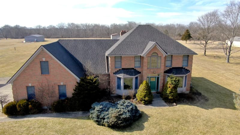 Brick colonial home with dark shingle roof